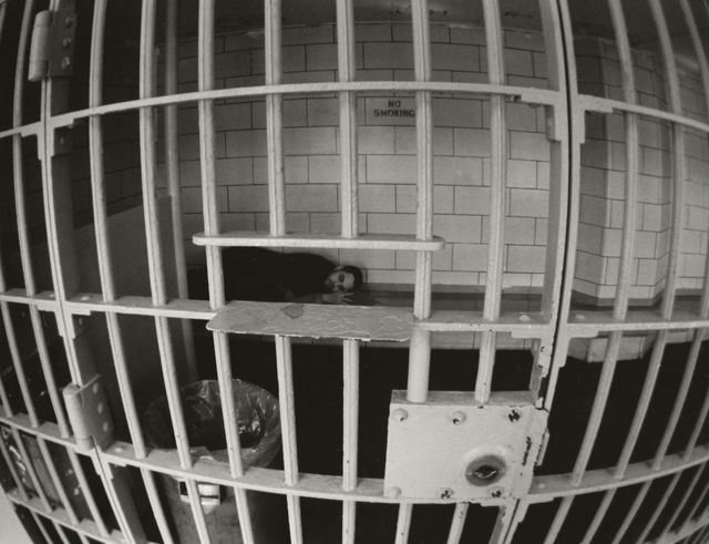 A man lying down in a jail cell